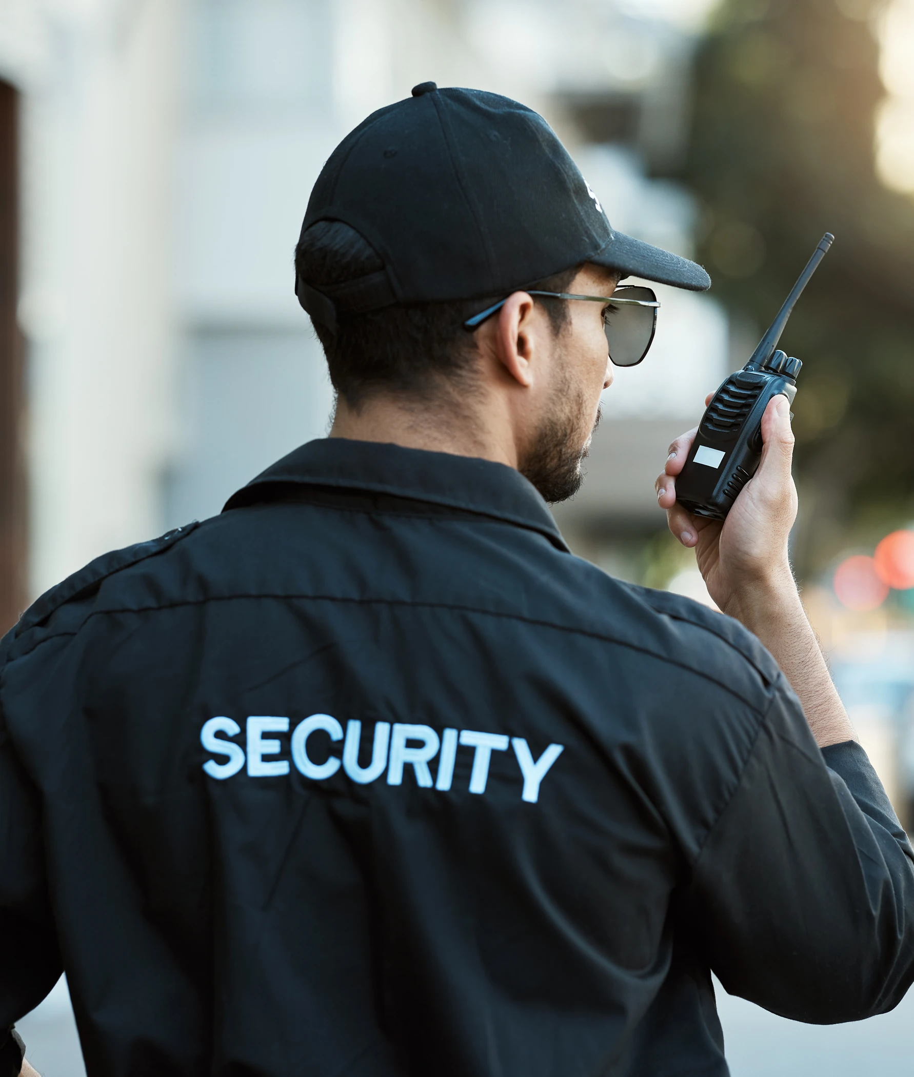 Security guard using walkie-talkie outside building.